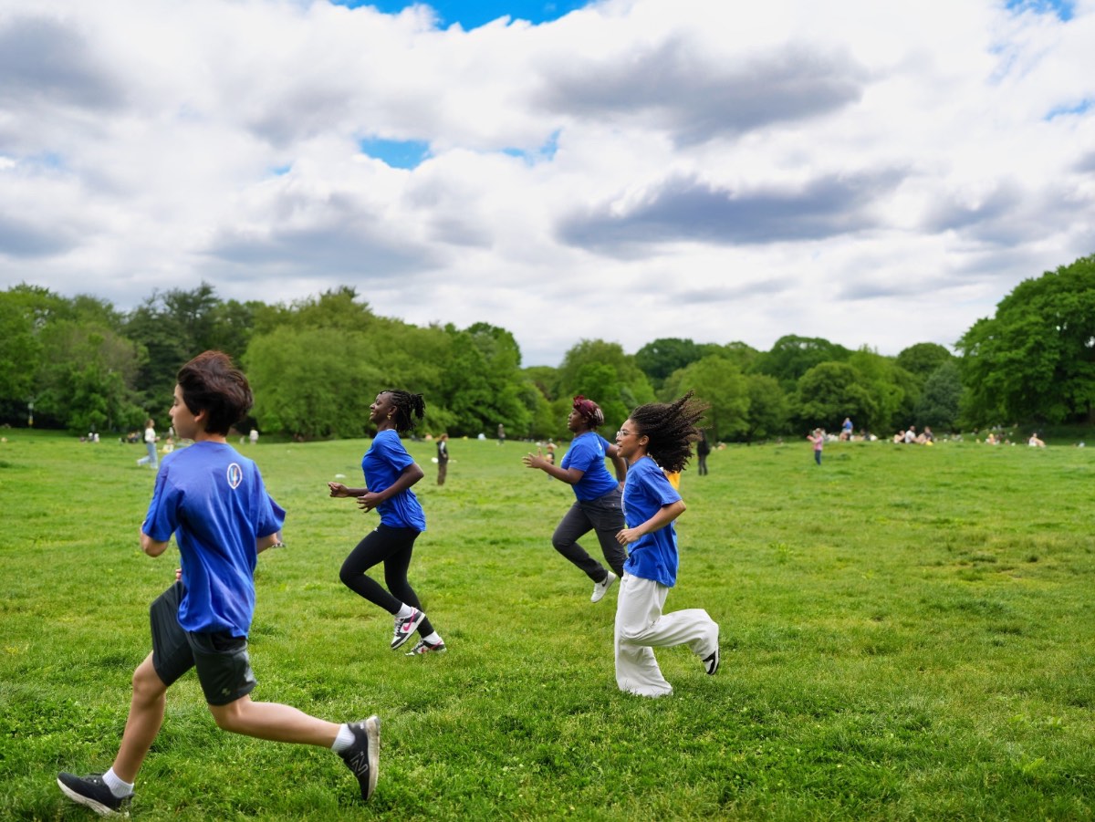Young people running together across a meadow in Prospect Park